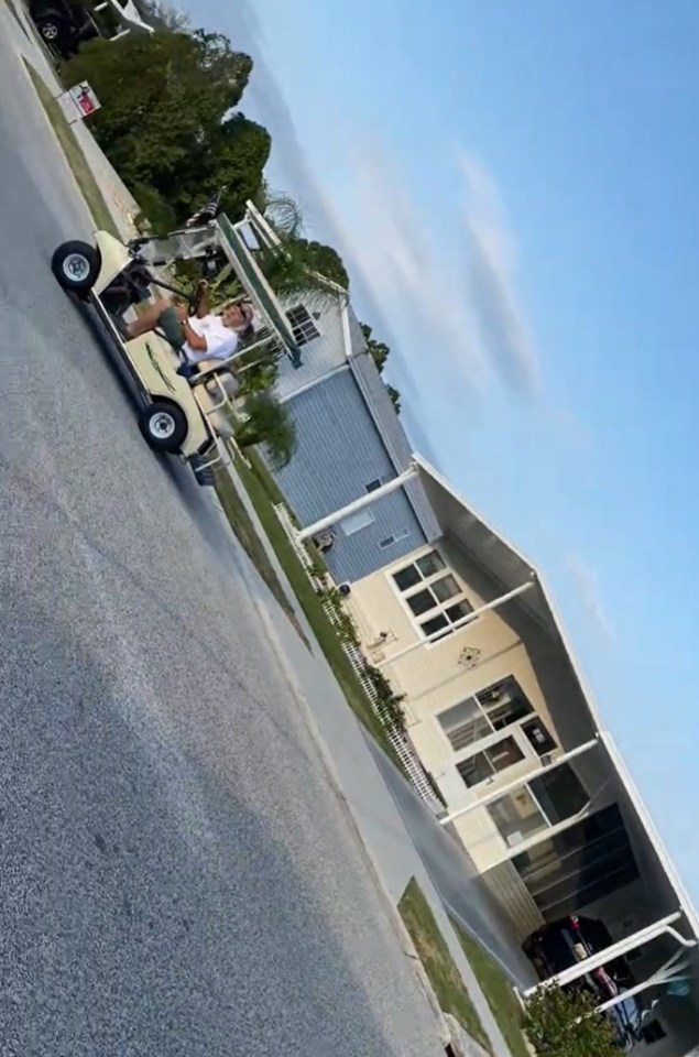 Man in golf cart on residential street.