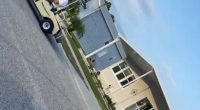 Man in golf cart on residential street.