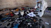 A woman in a protective suit documents clothing and shoes found at a crime scene.