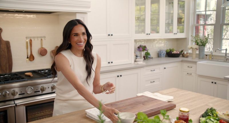 Meghan Markle in a kitchen, smiling.