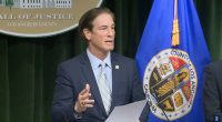 Man in suit speaking at Los Angeles County Hall of Justice press conference.