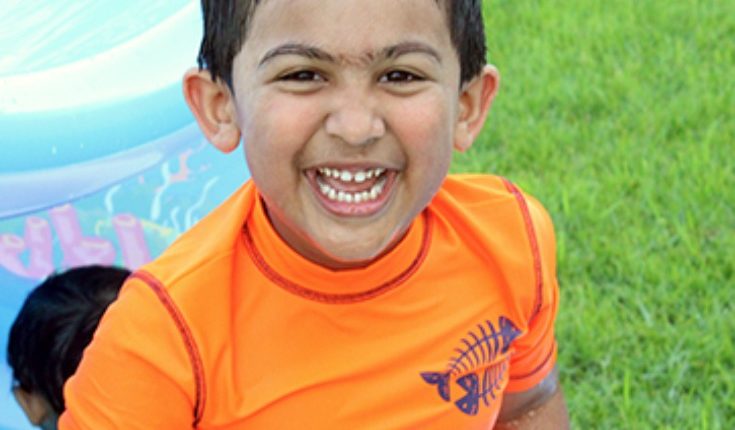A smiling 14-year-old boy wearing an orange shirt.