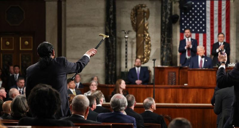 A congressman holds up a cane while President Trump addresses a joint session of Congress.