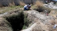 Two people examining a pit at a crime scene.