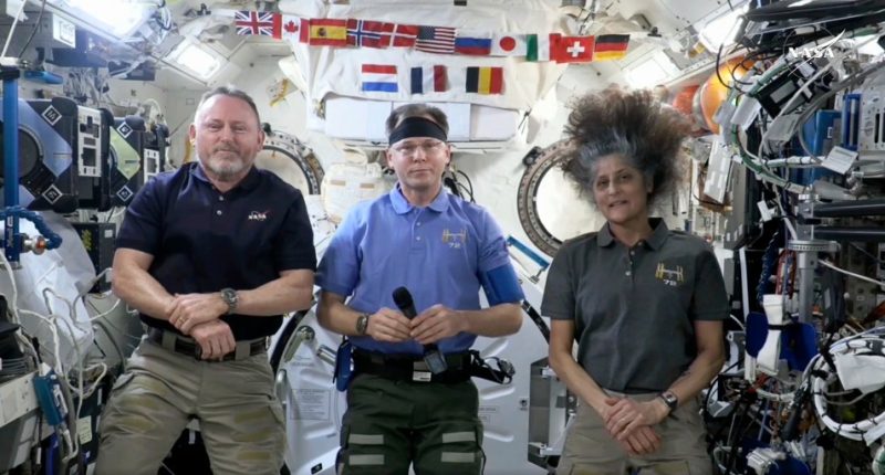 Three astronauts in the International Space Station give a news conference.
