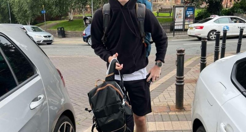 Owen Haggerty, a Royal Navy sailor, stands on a sidewalk with a backpack.