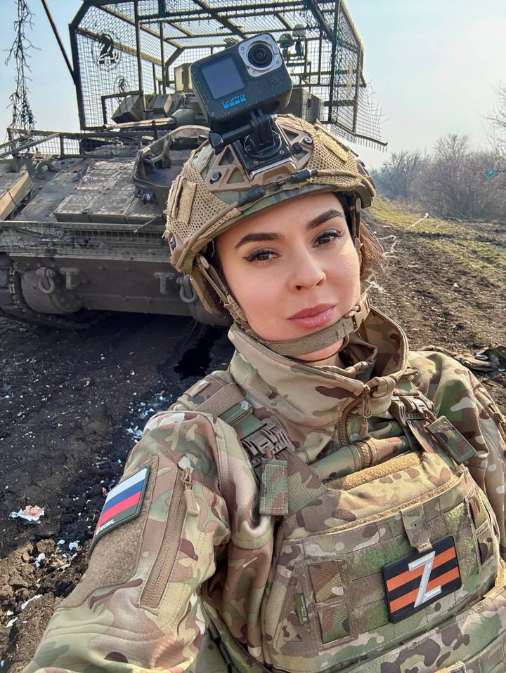 Anna Prokofyeva, a Russian state media correspondent, in military fatigues near a tank.