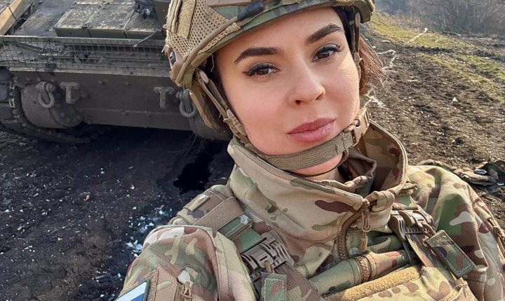 Anna Prokofyeva, a Russian state media correspondent, in military fatigues near a tank.
