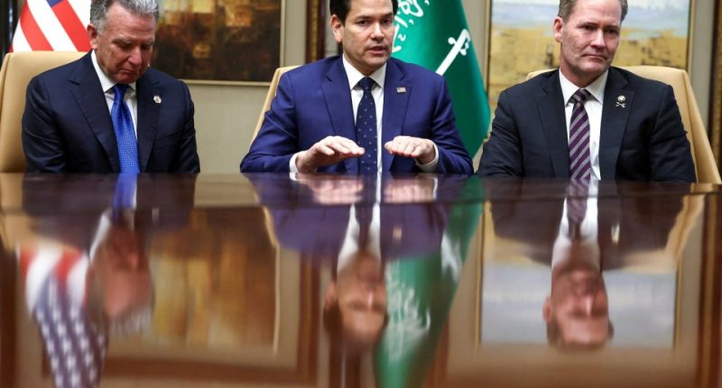 Three US officials seated at a table, speaking.