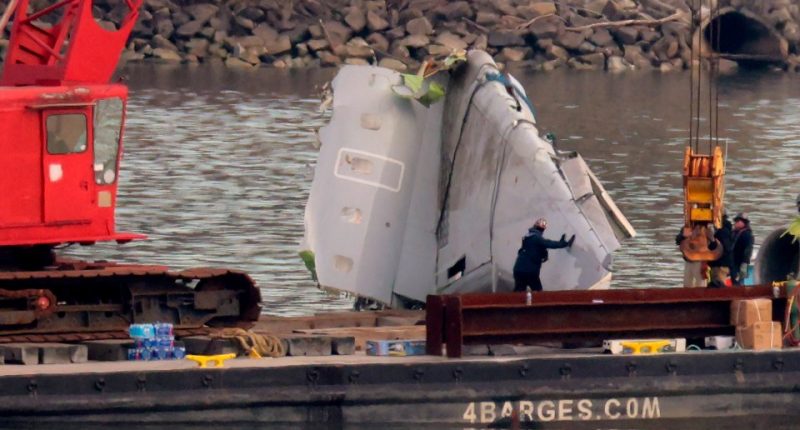 Salvage workers recovering wreckage of a plane crash from a river.