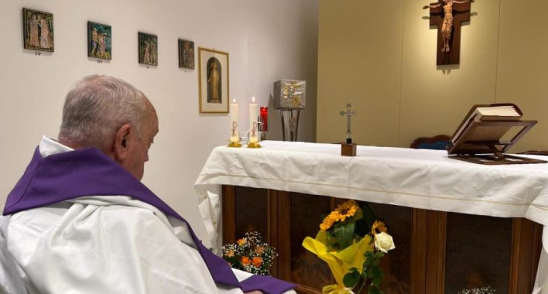 Priest in a wheelchair praying in a chapel.