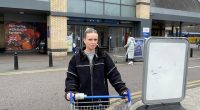 Woman with shopping cart of supplies outside Tesco.