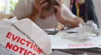 Eviction notice in foreground, stressed man in background.