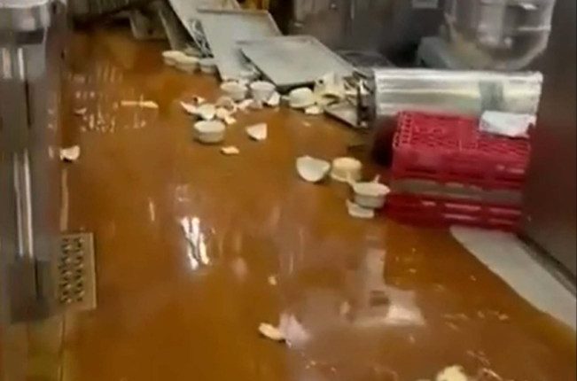 Flooded galley kitchen with spilled food and broken dishes.