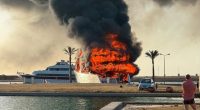 A boat engulfed in flames at a port.