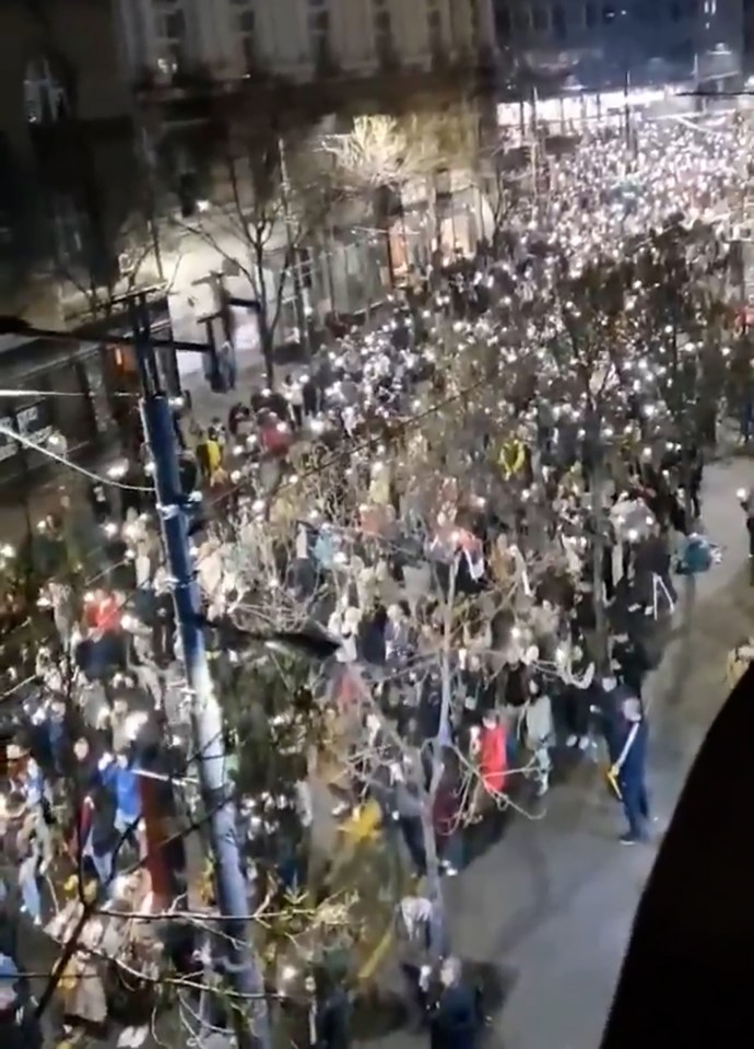 Protesters in Belgrade reacting to a sound during a demonstration.