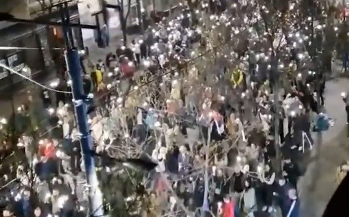 Protesters in Belgrade reacting to a sound during a demonstration.