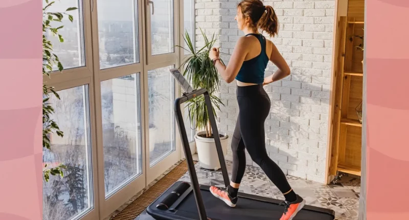 woman walking on treadmill in apartment in front of floor-to-ceiling windows