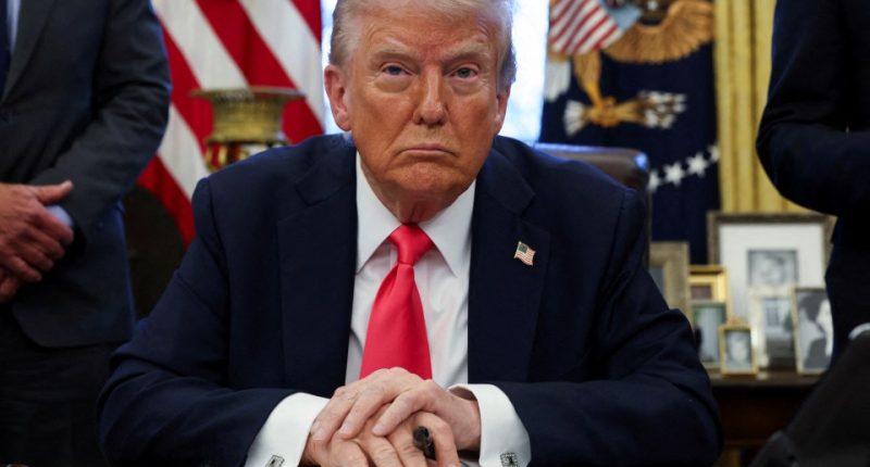 Donald Trump standing in front of American flags.