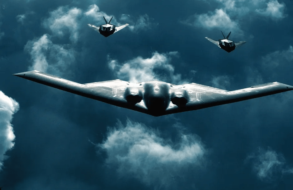 B-2 Spirit bomber with two fighter jets flying in formation.