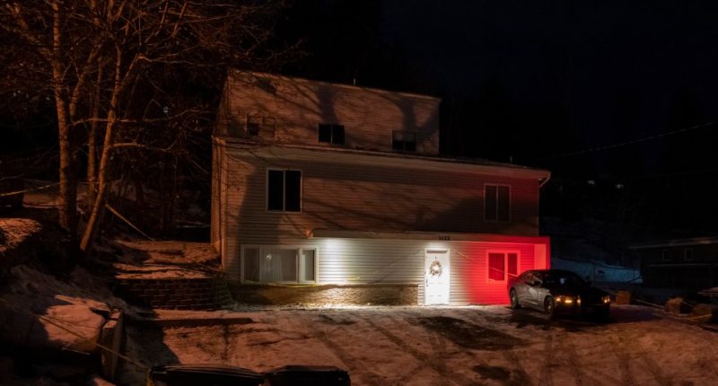 Nighttime photo of a house with police vehicle parked outside.