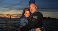 Couple embracing at sunset by the ocean.