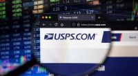 USPS.com website viewed on a computer screen with a blurred stock market in the background.