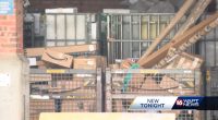 Mail packages piled high in metal cages at a USPS facility.