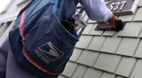 Postal worker placing mail in a mailbox.