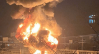 Large fire engulfing industrial storage tanks at night.