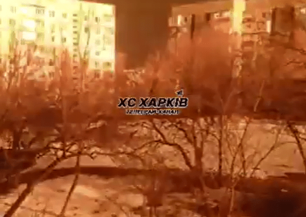 Nighttime view of apartment buildings illuminated by fire.