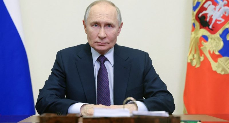 Vladimir Putin sitting at a desk.