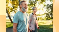 happy, mature couple walking outdoors for exercise on sunny day in park