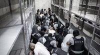 Law enforcement officers subduing prisoners in a prison cell block.