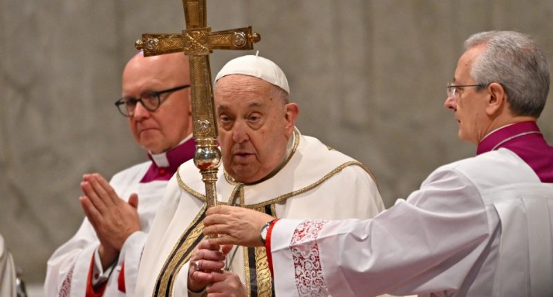 Pope Francis holding a cross during a mass.