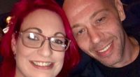 Close-up selfie of a woman with pink hair and glasses and a man.