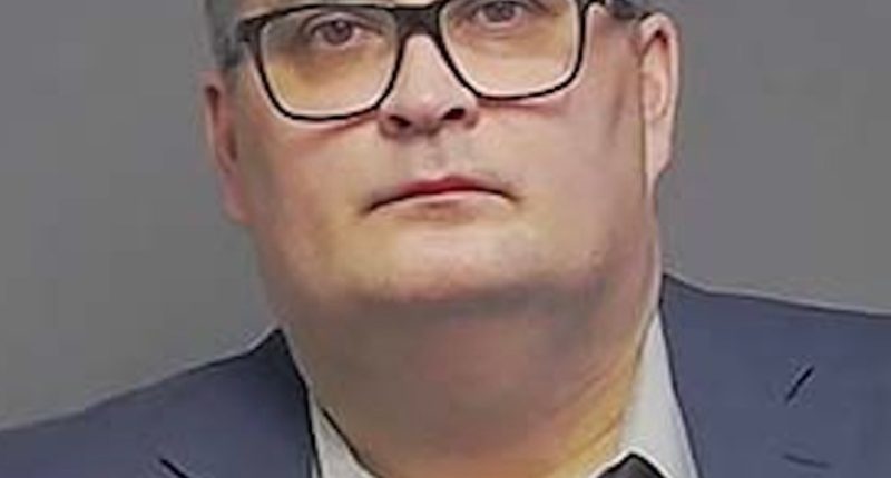 Photo of a man in a suit and glasses.