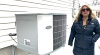 Woman standing next to a Carrier heat pump.