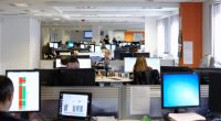Busy office with many employees working at computers.