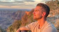 Man sitting and looking at a canyon at sunset.