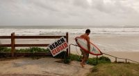 Former professional surfer Danny Wills heads out at main beach in Byron bay before the arrival of Cyclone Alfred.