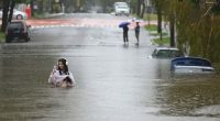 A resident wades in flooded Edmonstone Street in the suburb of Newmarket in Brisbane.