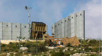 An Israeli soldier takes up a position in front of a battery of an Iron Dome air defense system near Jerusalem on April 15, 2024.