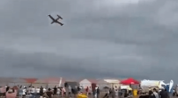 Small plane flying over a crowd of people.