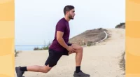 man in maroon t-shirt and black shorts doing walking lunges outdoors by the beach