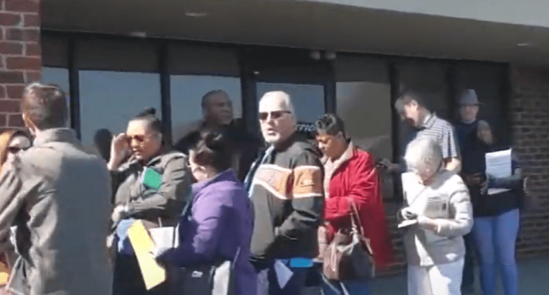 Long line of people waiting outside a building.