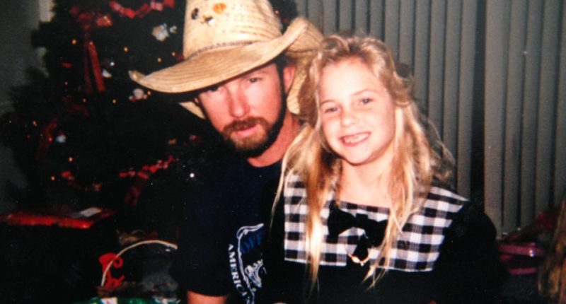 Photo of a father and daughter near a Christmas tree.