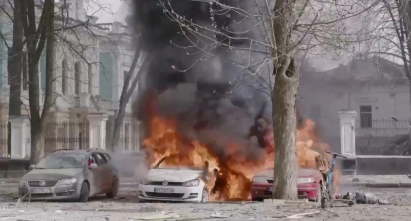 Aftermath of a missile strike in Ukraine showing burning cars and debris.