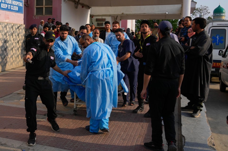 Paramedics carry a wounded person on a stretcher outside a hospital.