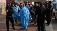 Paramedics carry a wounded person on a stretcher outside a hospital.